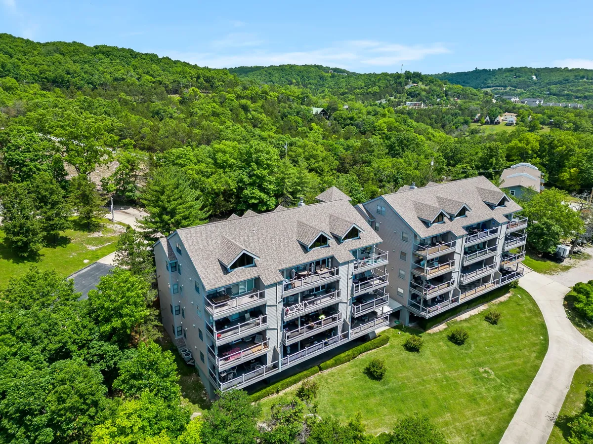 The image displays a three-story building surrounded by lush greenery, with balconies furnished for outdoor relaxation. The setting is quiet and inviting, suggesting privacy and opportunities for couples to unwind amidst nature.